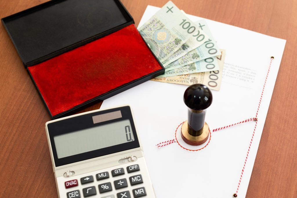 a calculator, contract, money, and notary stamp